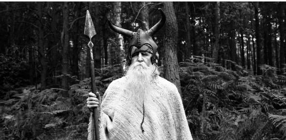 a dog standing on a sidewalk next to a fence