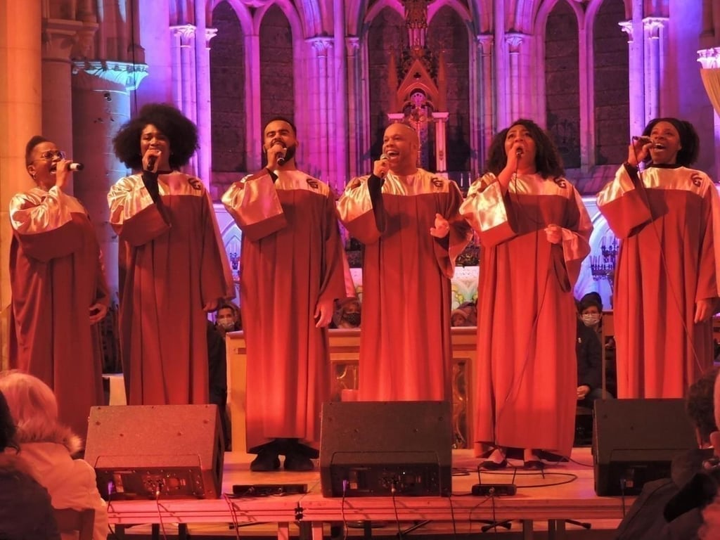 Choir singing in a church against an ornate altar background, with a conductor in the foreground.
