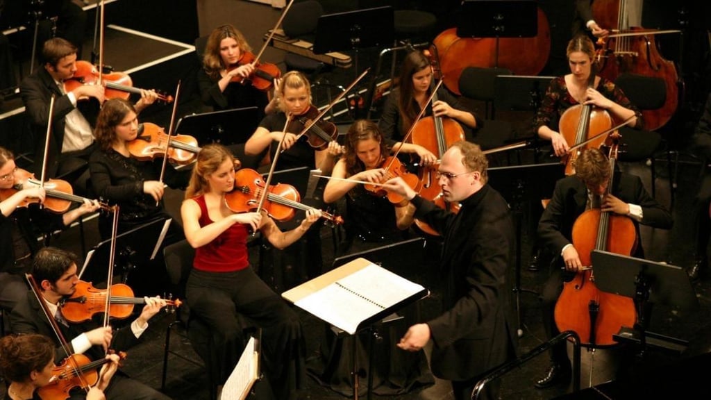 A conductor and orchestra performing in a concert hall