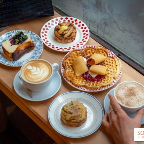 A cafe paris sign glows brightly in the dusk.