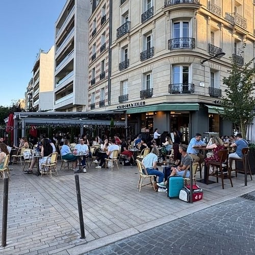 a group of people sitting at tables outside of a restaurant