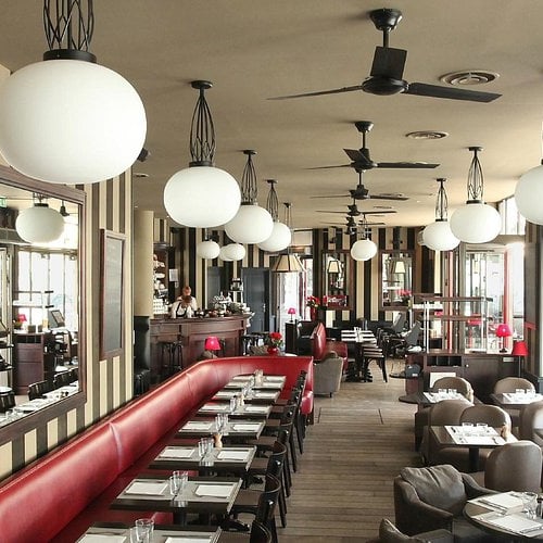 A group of people sitting at tables in front of a building