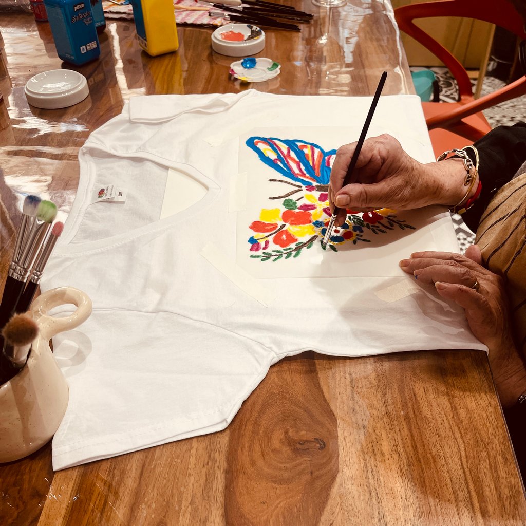 Yellow building with light blue shutters and pink flowers.
