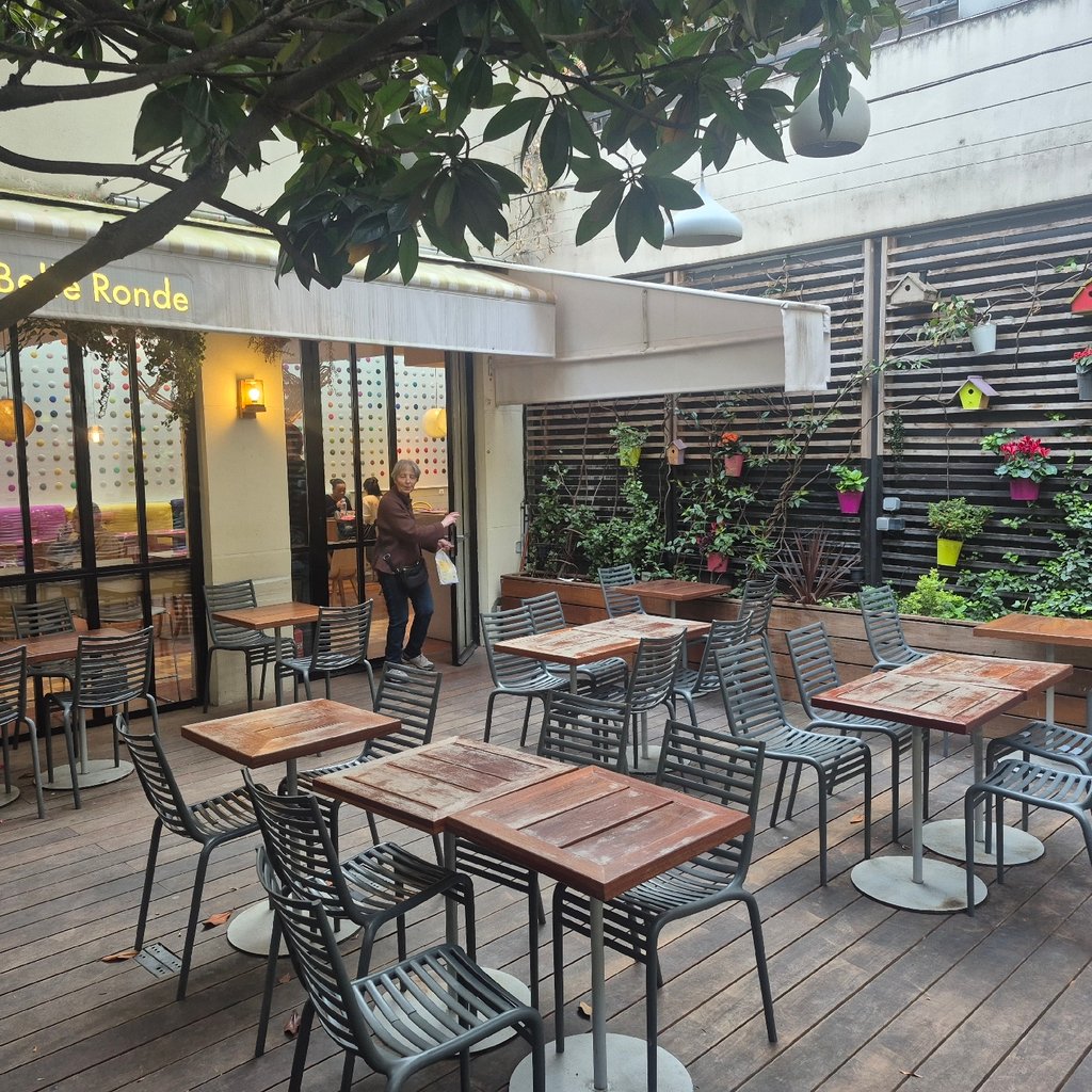 Rural road leading past stone buildings under cloudy sky.